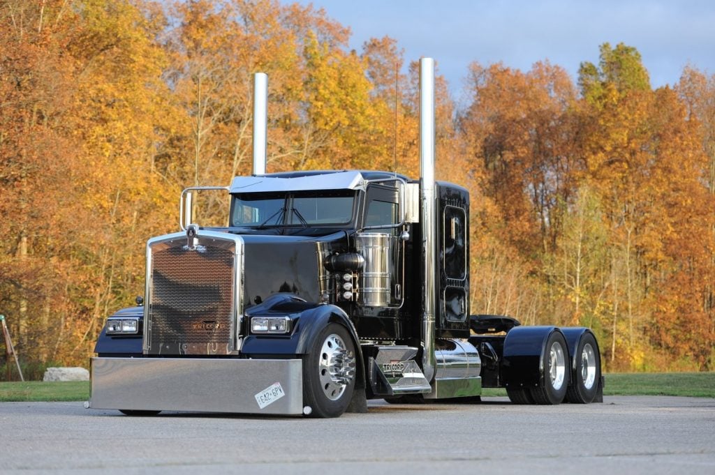 A photo of a black heavy truck in front of autumn foliage, for marketing the 2018 Wowtrucks calendar